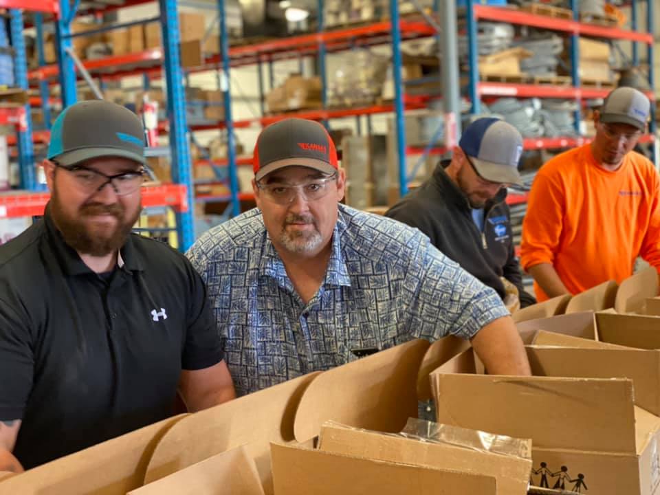 Two Kansas Electric employees smiling while packing meals