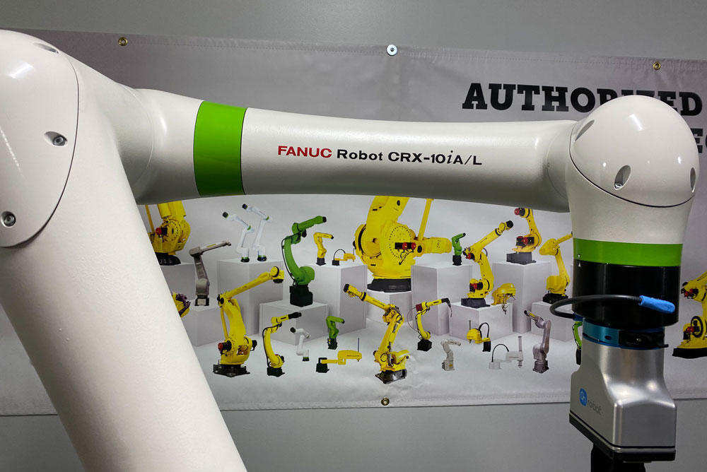 Yellow robotic arm in front of a large manufacturing machine